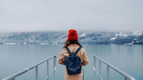 Rear view of woman standing amidst railing while looking at sea