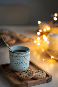 Cozy evening, mug of drink, holiday decorations, candles and lights garlands. christmas background 