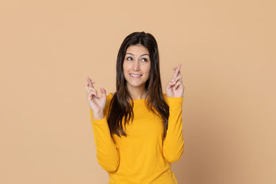 Portrait of a smiling young woman against yellow background