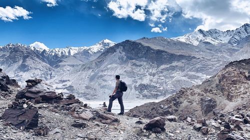 Full length of man standing on snowcapped mountain against sky