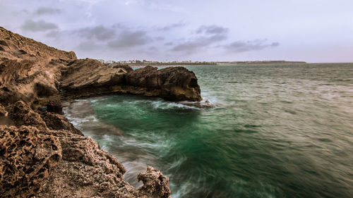 Rock formation in sea against sky