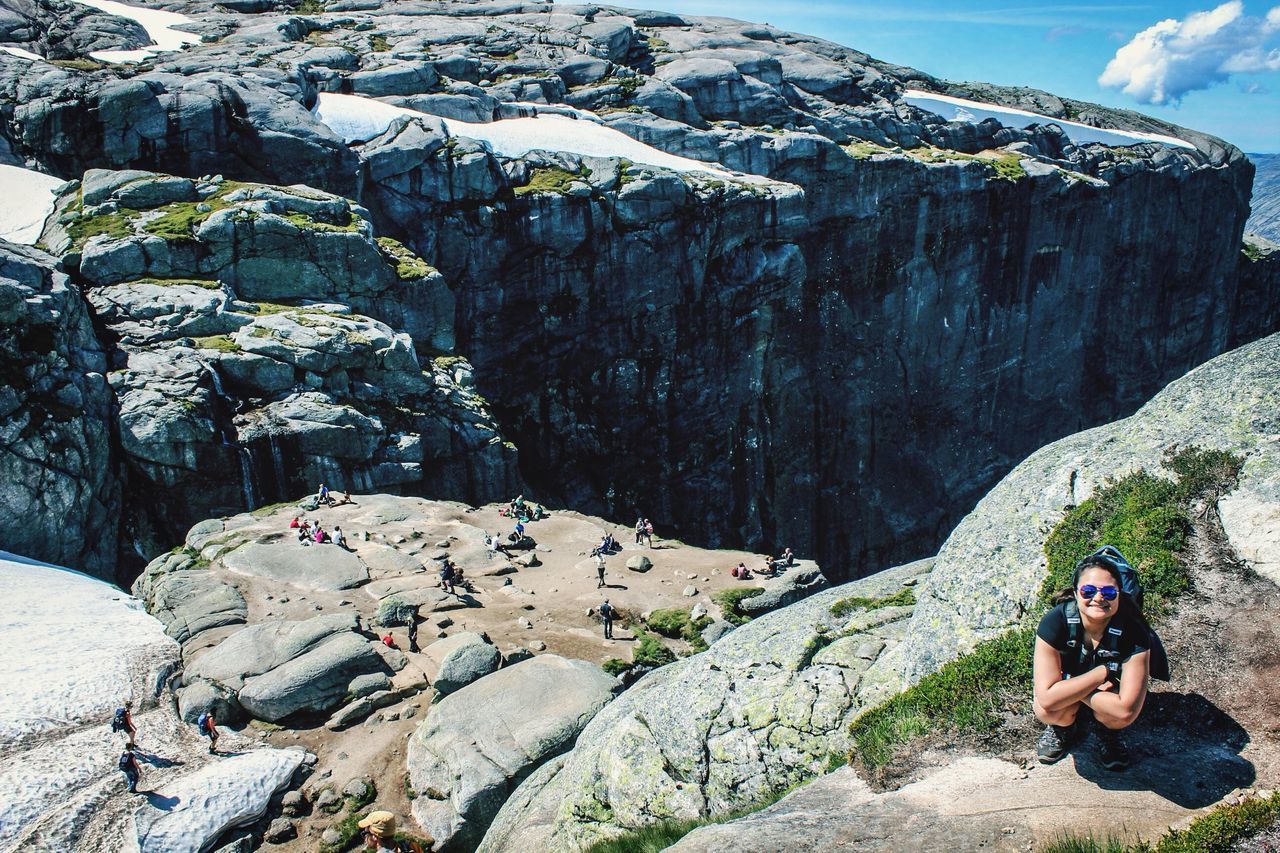 lifestyles, leisure activity, rock - object, casual clothing, full length, men, person, mountain, vacations, nature, sitting, water, young adult, rock formation, rear view, tourist, day, beauty in nature