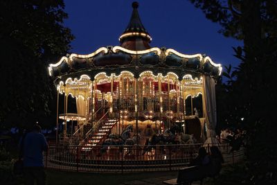 Illuminated carousel against clear sky at night