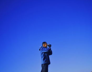 Man photographing against clear blue sky