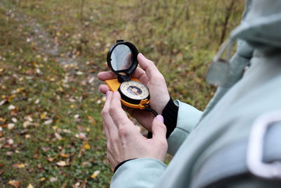 A women in a blu coat holds a compass in her hand and navigates the surroundings, the autumn forest