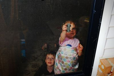 High angle view of brother and sister playing on window