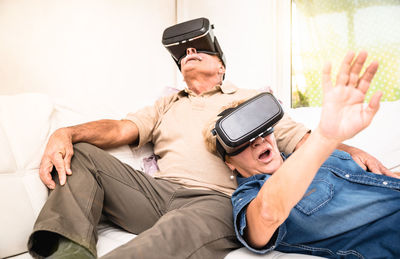 Happy friends wearing virtual reality simulator at home