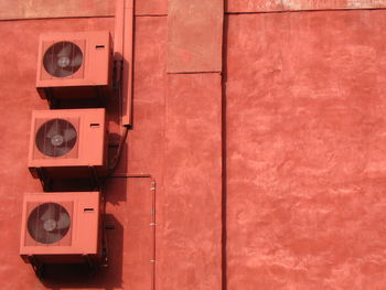 Low angle view of air conditioners on brown wall