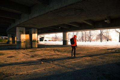 Rear view of man standing under bridge