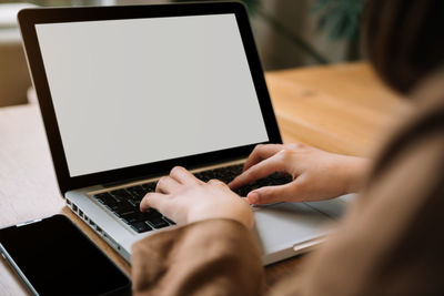 Midsection of woman using laptop on table