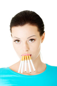 Close-up of young woman smoking cigarettes standing over white background