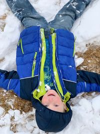 High angle view of boy lying on snow covered land