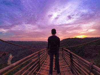 Rear view of man standing on footbridge