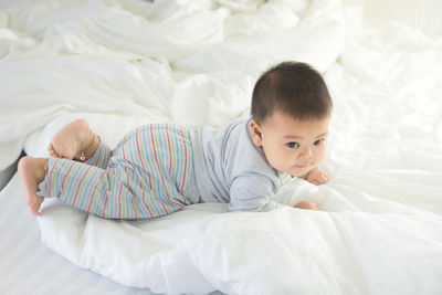 High angle view of cute boy lying on bed at home