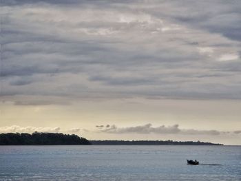 Boat sailing in sea against cloudy sky