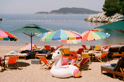 Deck chairs and parasols on beach against sky