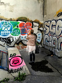 Full length of woman standing on graffiti