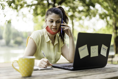 Woman using phone while sitting on table