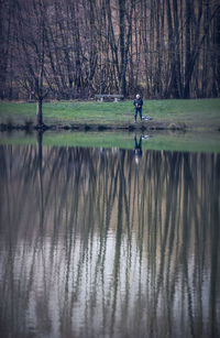 Distant view of man standing by lake at park