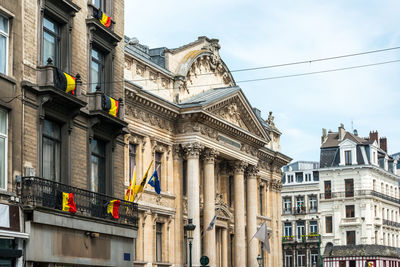 Low angle view of belgian flags on building in city against sky