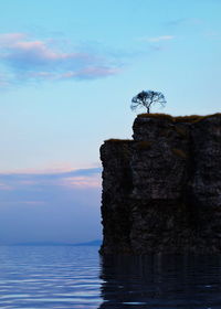 Rock formation by sea against sky