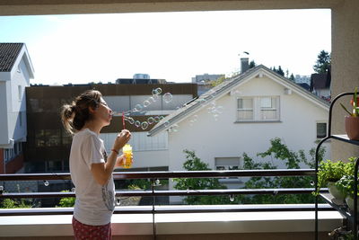 Woman standing by buildings against clear sky