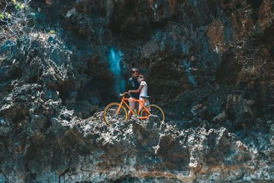 People with bicycle on rock formation in water