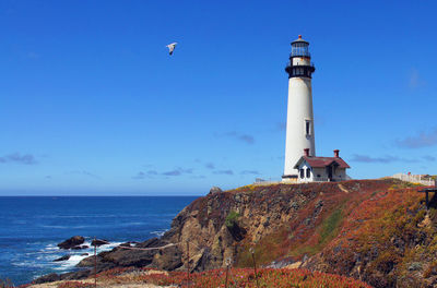 Lighthouse by sea against sky