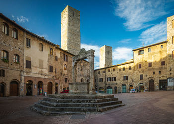 Central place with fountain in medieval tuscany town san gimignano, italy against sky