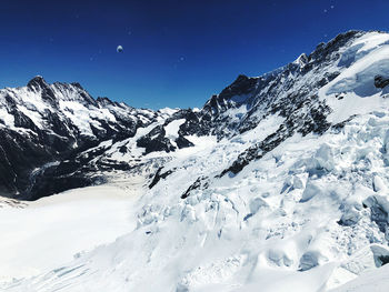 Scenic view of snowcapped mountains against blue sky