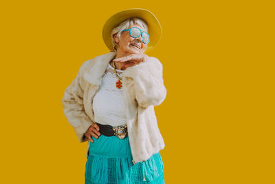 Smiling woman standing against yellow background