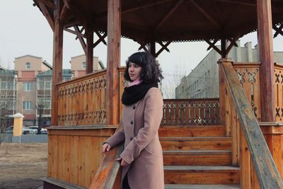 Side view of young woman in warm clothing looking away while standing on steps