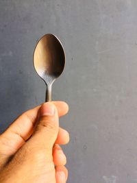 Man holding spoon against gray wall