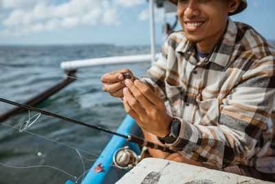 Rear view of man holding boat in sea