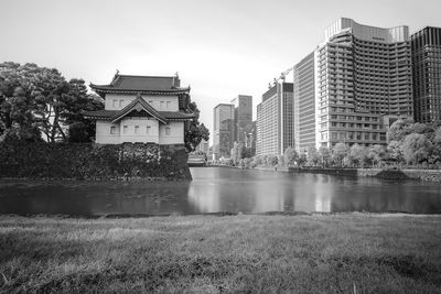 Buildings by lake against sky in city