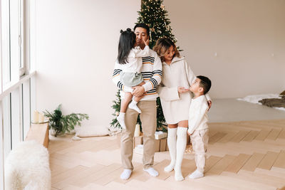 An asian multi-racial family with two children celebrate the christmas holiday in a decorated indoor