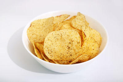 Close-up of potato chips in bowl on white background