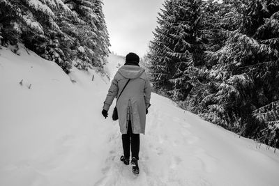 Rear view of man walking on snow covered mountain