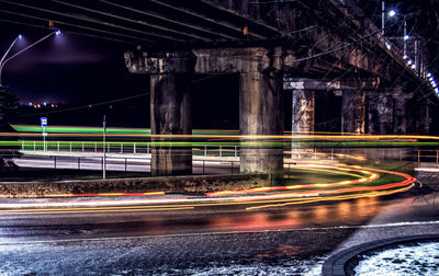 Colorful light trails on street below bridge at night