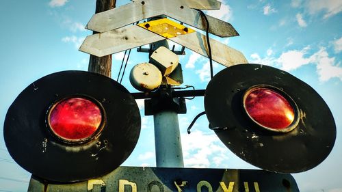 Low angle view of railroad crossing sign against sky