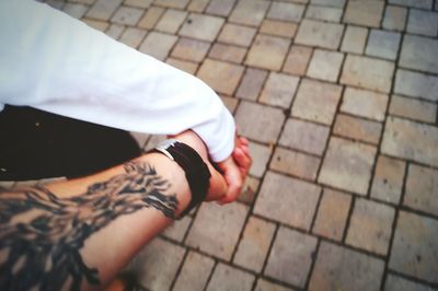 Cropped image of couple holding hands on footpath