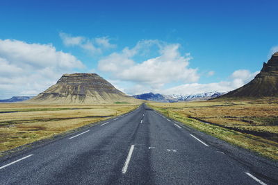 Road passing through landscape against cloudy sky