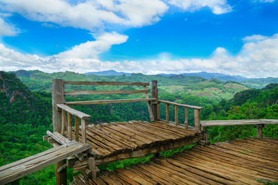 Wooden railing on landscape against sky