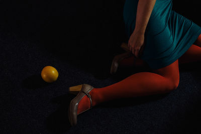 Low section of woman by orange on floor