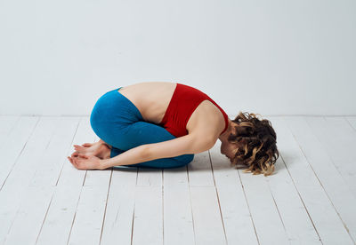 Young woman lying down on floor against white background