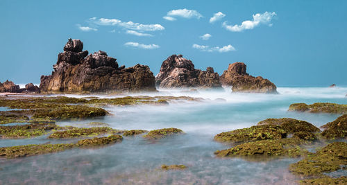 Scenic view of rocks in sea against sky