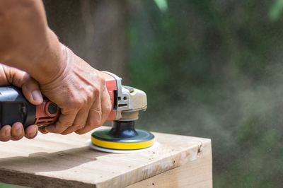 Cropped hands of person using work tool on wood