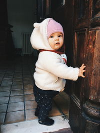 Side view portrait of cute baby girl wearing warm clothing while standing at home