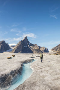 Dramatic view of climber approaching mt. loki, baffin island, canada.