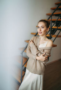 Portrait of young woman standing against wall